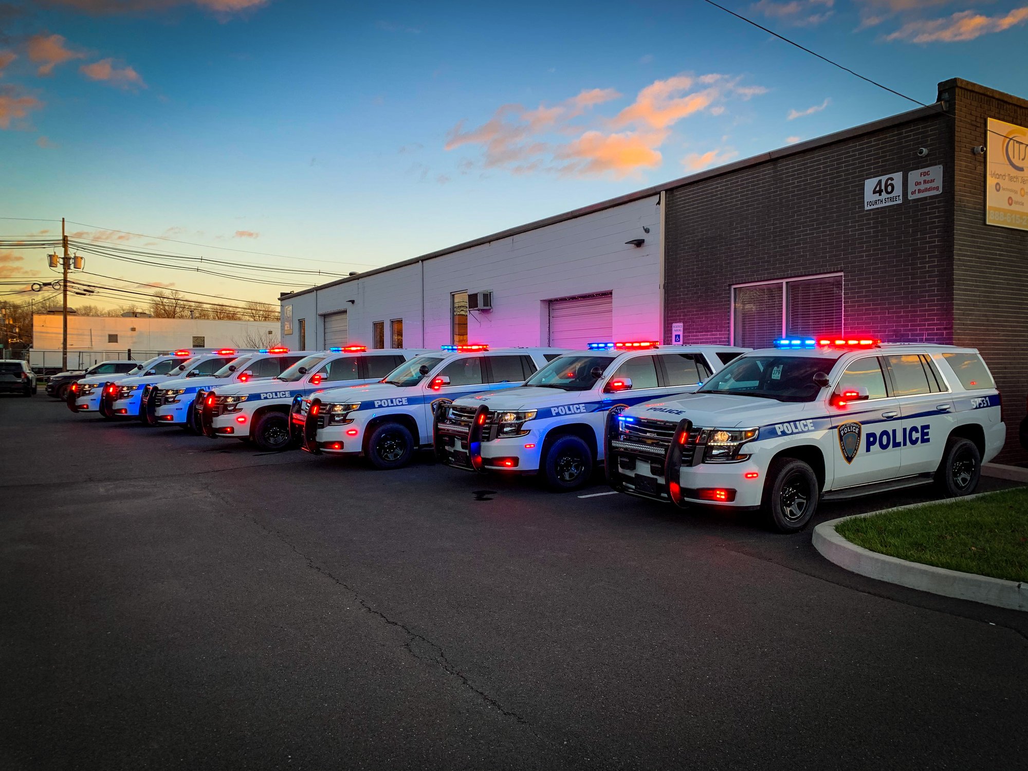row of fully lit police vehicles in parking lot